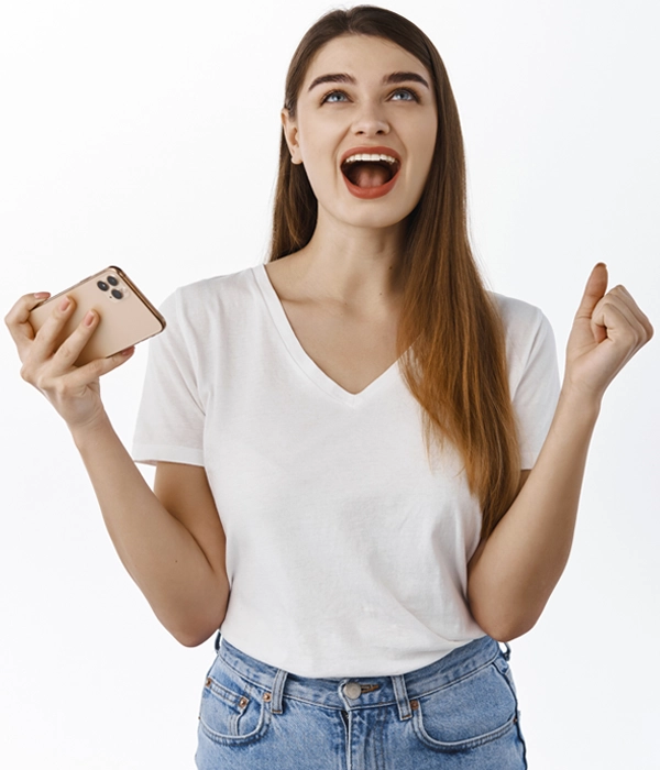 Happy young woman celebrating with smartphone